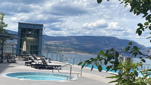 Ein Poolbereich mit Liegestühlen und Blick auf einen See und Berge.