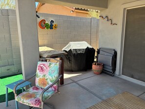 An outdoor patio area with a covered grill, a chair with floral upholstery, and a sign that reads 'Cafe'. - Winter in AZ!! Early bird pricing!! 1000.00 DOLLARS OFF for any 2 month stay!! (Scottsdale)
