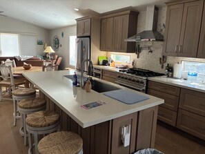 A kitchen with a central island, wooden cabinets, a stainless steel refrigerator, and a gas stove. - Winter in AZ!! Early bird pricing!! 1000.00 DOLLARS OFF for any 2 month stay!! (Scottsdale)