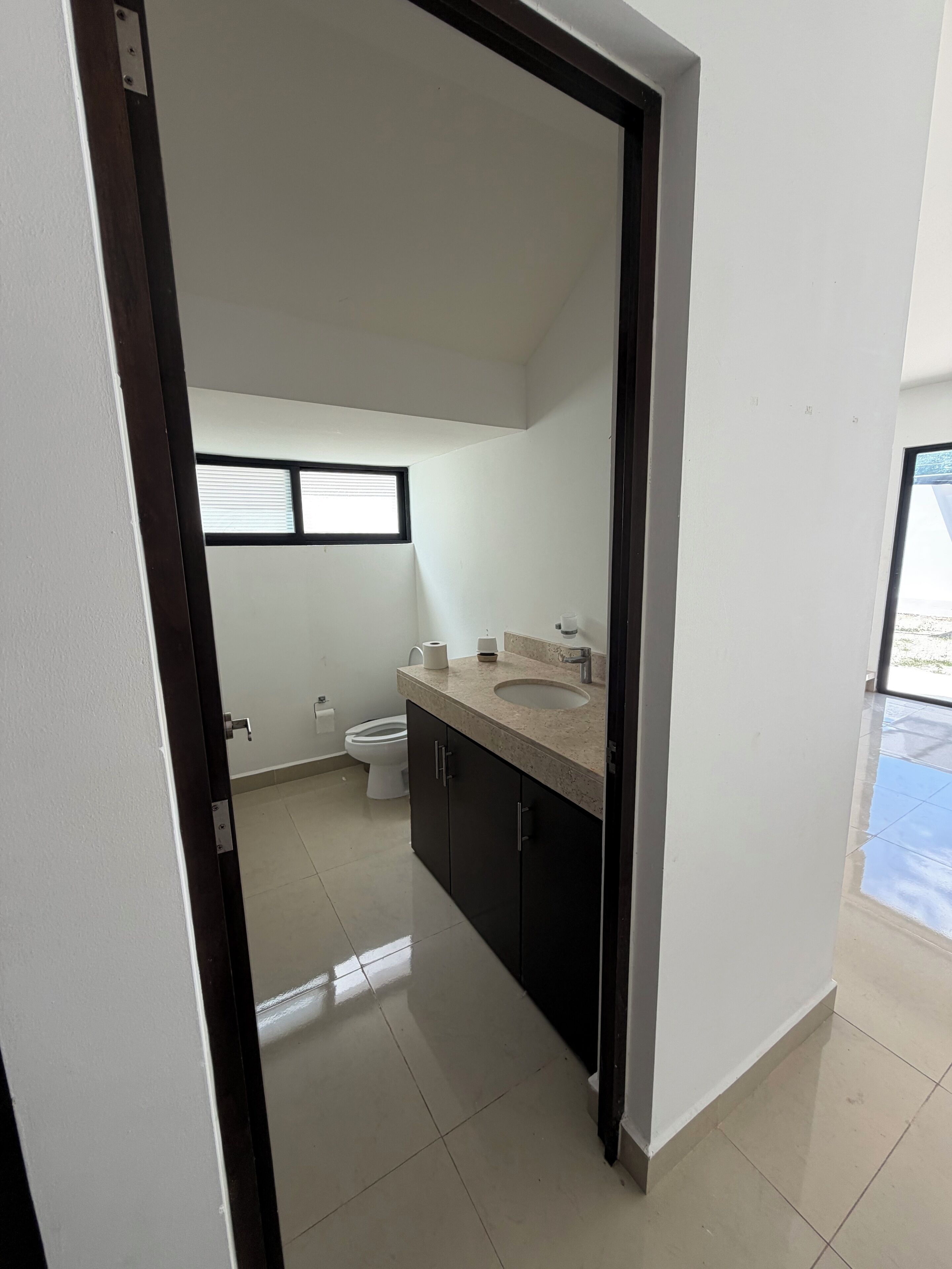 Une salle de bain avec un lavabo, des toilettes et une fenêtre.