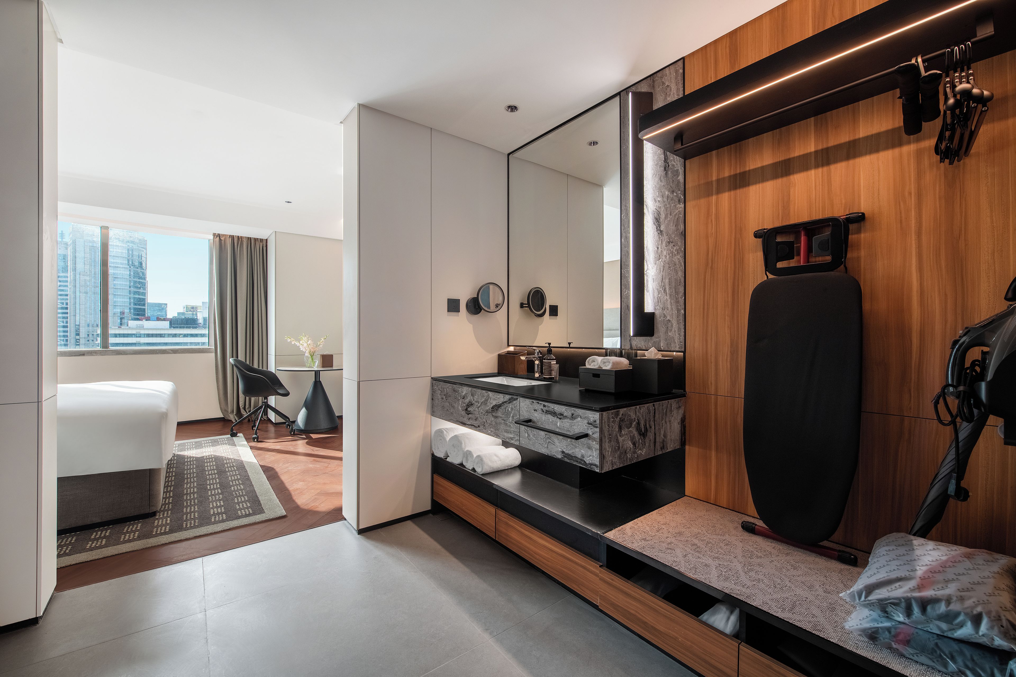 Habitación de hotel moderna con un espejo grande, una estación de ejercicio, un escritorio y vistas a la ciudad.