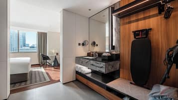 Een moderne hotelkamer met een grote spiegel, een fitnessapparaat, een bureau en uitzicht op de stad.