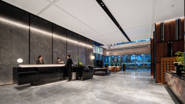 Un moderno vestíbulo de hotel con mostrador de recepción, zona de estar y grandes ventanales.