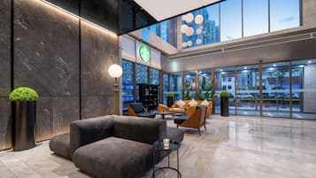 A modern interior with seating, a Starbucks sign, and large windows.