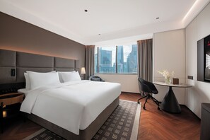A hotel room with a large bed, a desk, and a chair. There is a window with a city view. - Intercity Shanghai Lujiazui Central  (Shanghai)