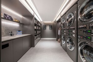 A modern laundry facility with multiple washing machines, a water dispenser, and informational signs.
