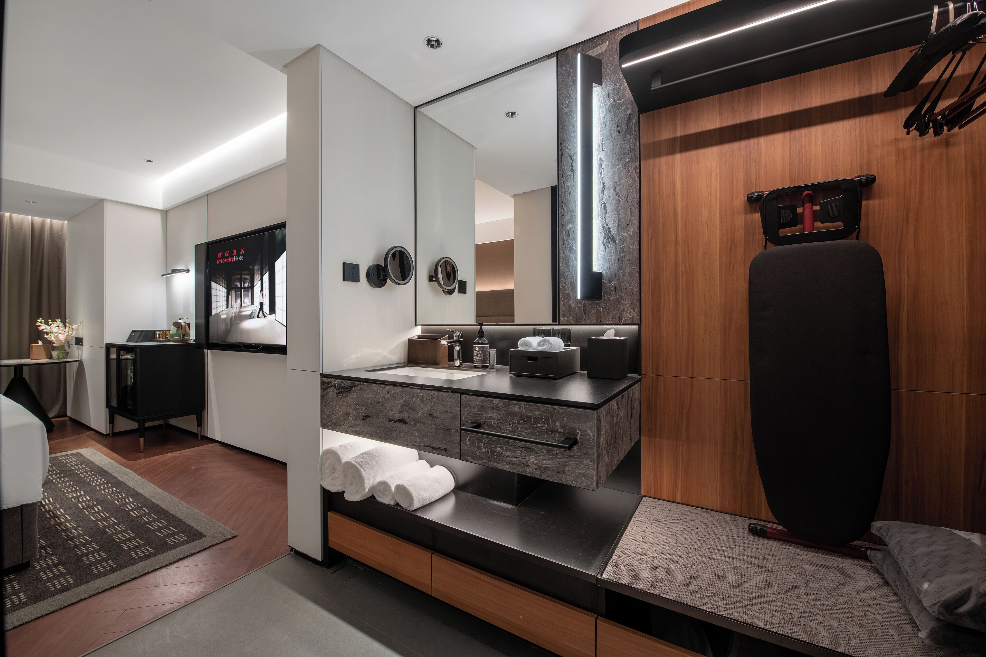 A modern bathroom with a large mirror, a black vanity, and a towel rack.