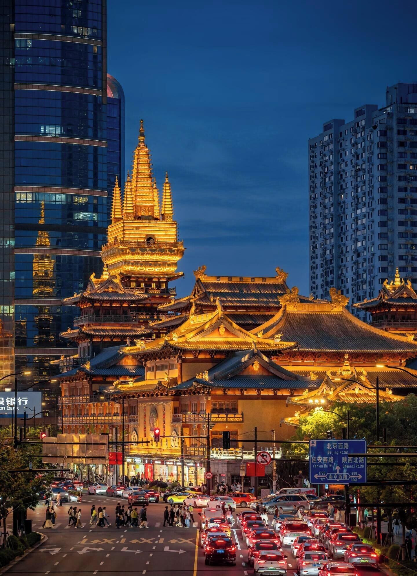 A traditional Chinese building with multiple tiers and golden roofs, surrounded by modern high-rise buildings.