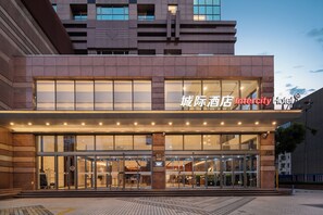 A hotel entrance with a modern facade, large glass windows, and a sign indicating 'Intercity Hotel'.