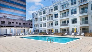 A rooftop pool with lounge chairs and a building with balconies. - Luxury Apt Downtown with Pool & Gym (Stamford, CT)