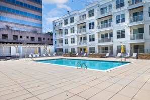 Ein Pool auf dem Dach mit Liegestühlen und ein Gebäude mit Balkonen.