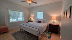 A bedroom with a bed, two bedside tables, a ceiling fan, and windows with blinds. - Downtown Harbor Springs cottage with 4 bedrooms, 2 baths, yard, and grill. (Harbor Springs)