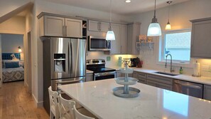 Una cucina moderna con elettrodomestici in acciaio inossidabile, un piano di lavoro in marmo e illuminazione a sospensione.