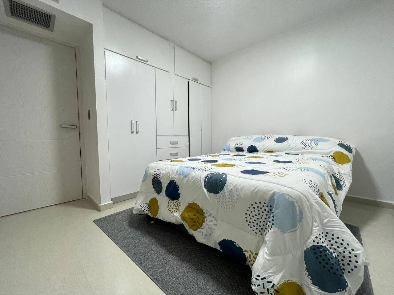 Une chambre à coucher avec un lit, une armoire et un tapis gris.