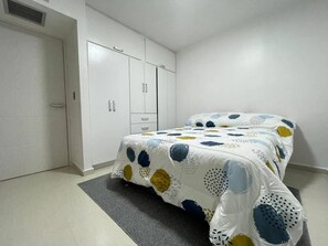 Ein Schlafzimmer mit einem Bett, einem Kleiderschrank und einem grauen Teppich.