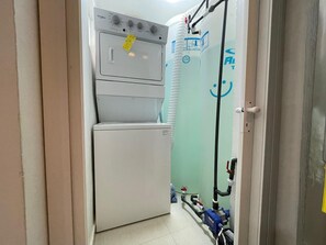 Ein Waschraum mit einer Whirlpool Waschmaschine und einem Trockner, einem Warmwasserbereiter und freiliegender Sanitärinstallation.