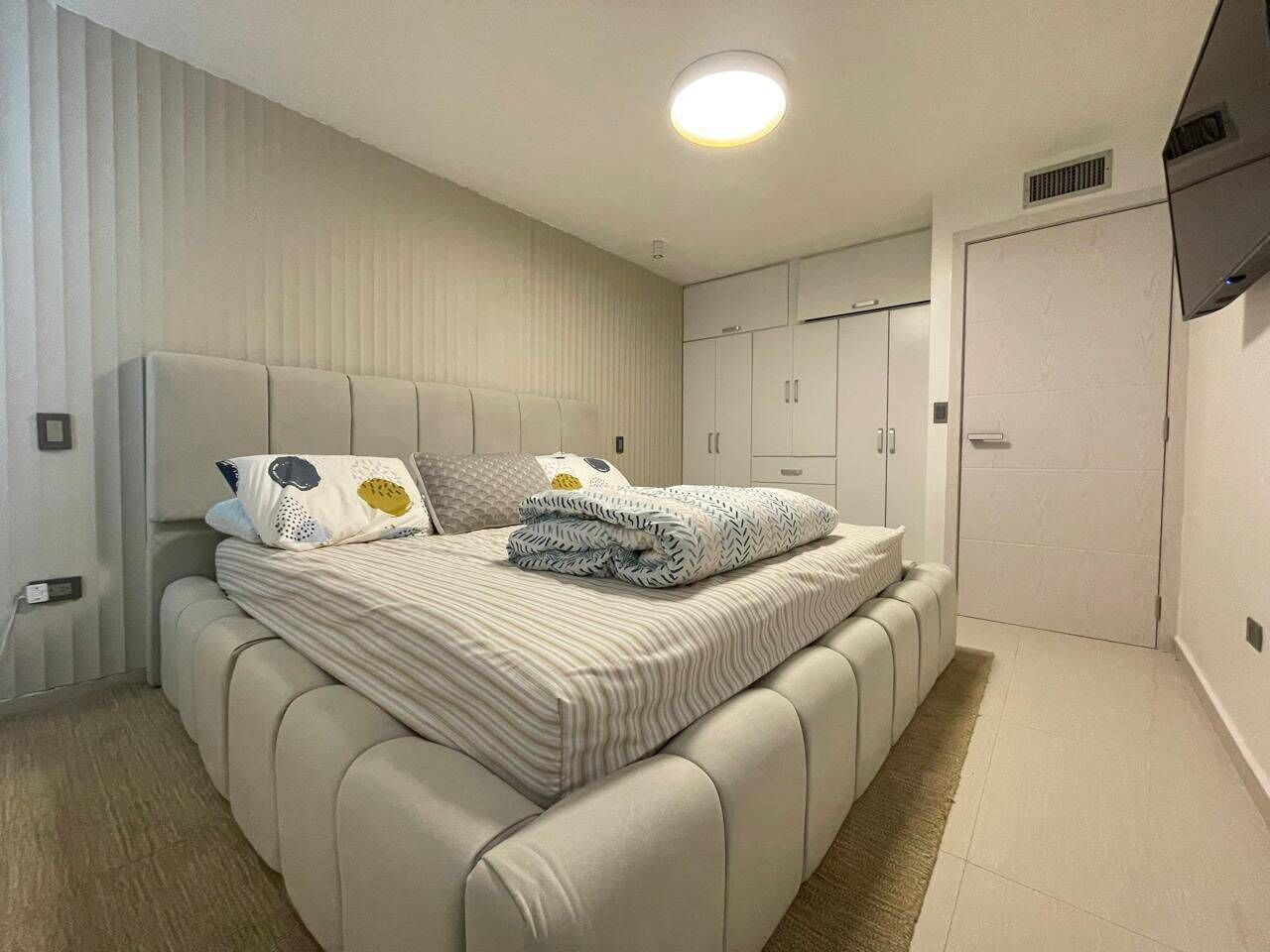 Una camera da letto moderna con un letto grande, un armadio e un televisore a parete.