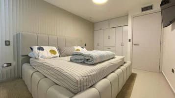Una camera da letto moderna con un letto grande, un armadio e un televisore a parete.