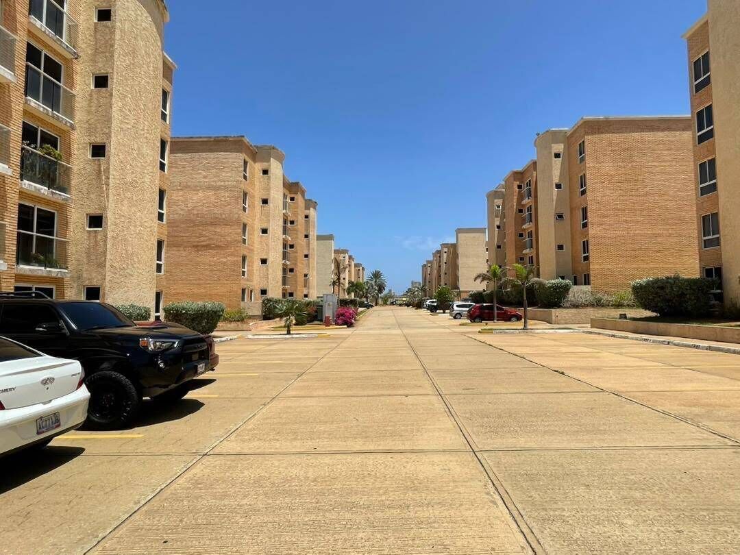 Un quartiere residenziale con edifici a più piani, un marciapiede lastricato e veicoli parcheggiati.