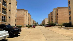 Un quartier résidentiel avec des immeubles à plusieurs étages, un chemin piétonnier pavé et des véhicules stationnés.