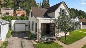 Ein zweistöckiges Haus mit einer Stein-Fassade, einer Garage und einem gepflegten Rasen.
