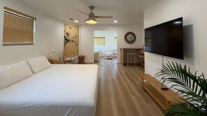 Une chambre d’hôtel équipée d’un lit, d’une télévision, d’un ventilateur de plafond, d’un bureau et d’une chaise.