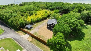Een groot landgoed met een huis, omringd door weelderige begroeiing en een meer op de achtergrond.