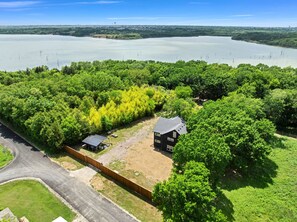 Uma propriedade extensa com uma casa rodeada por vegetação densa e um lago ao fundo.