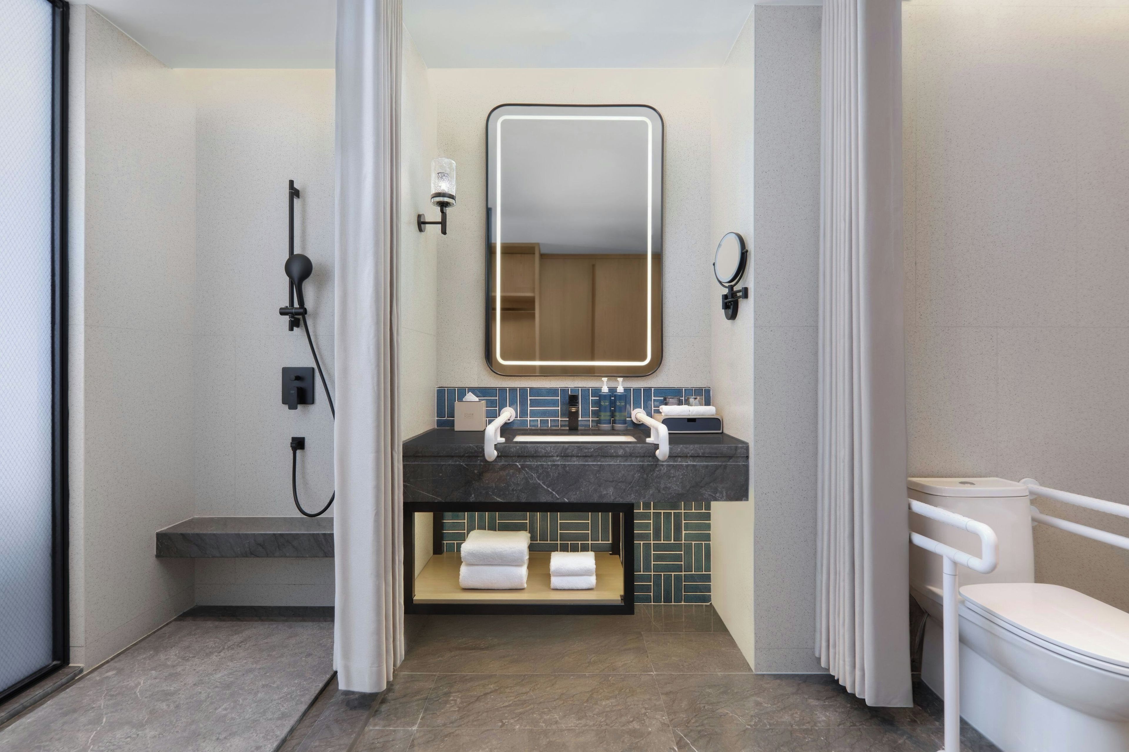 A modern bathroom with a shower, a sink with a mirror, and a toilet.