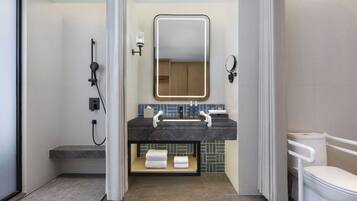A modern bathroom with a shower, a sink with a mirror, and a toilet.