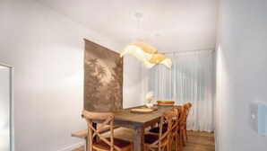 A dining area with a wooden table and chairs, a hanging light fixture, and a large painting on the wall. - Rye beach getaway (Rye)