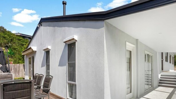 A modern house with a covered patio, a dining area with chairs and a table, and a staircase leading to the upper level. - Rye beach getaway (Rye)