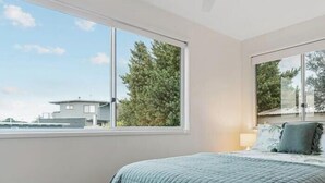 A bedroom with a bed, a ceiling fan, and large windows. - Rye beach getaway (Rye)