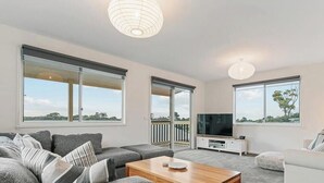 A modern living room with a sofa, coffee table, and a flat-screen TV. - Rye beach getaway (Rye)