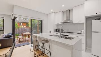 A modern kitchen with a central island, white cabinetry, and a view to a backyard patio.