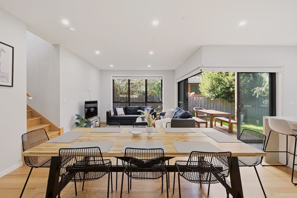 A modern interior with a dining area, a sofa, and a staircase.