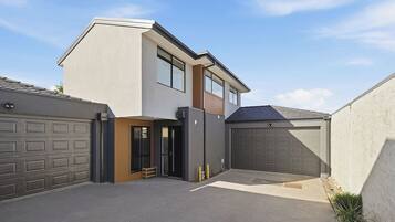 A modern two-story house with a garage, a covered entryway, and a small outdoor seating area.