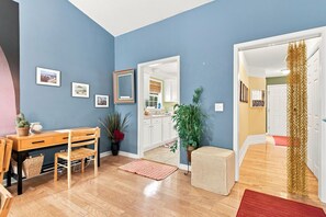 Une pièce avec une table à manger en bois, des chaises, une plante en pot et un miroir au mur.