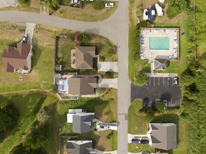 Vue aérienne d’un quartier résidentiel avec des maisons, une piscine et un parking.