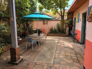 A patio with a table and chairs, a green umbrella, and potted plants. - We Conquered Colonial - Macarena (Bogota)