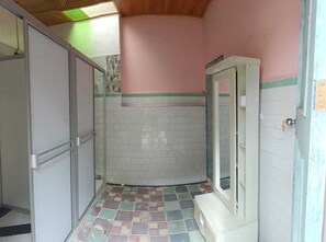 A bathroom with a tiled floor, a shower area, and a door. - We Conquered Colonial - Macarena (Bogota)