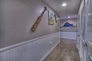 A hallway with a white wainscoting, a sports-themed wall art, and a blue mural. - Sterling Breeze PCB | 3BR Luxury near Pier Park (Panama City Beach)