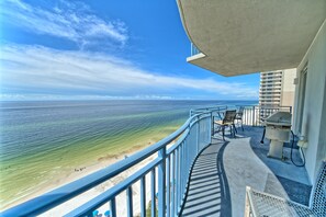 A balcony with a view of the ocean, a barbecue grill, and outdoor furniture. - Sterling Breeze PCB | 3BR Luxury near Pier Park (Panama City Beach)