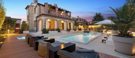 A poolside area with lounge chairs and a stone building in the background.
