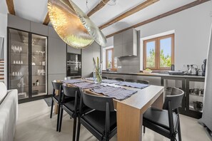 A modern kitchen with a dining area, featuring a large island, built-in appliances, and a view of the outdoors. - Villa Aurelia – Luxury Istrian Stone Villa with Pool, Jacuzzi and Sauna by Istrabook (Čabrunići)