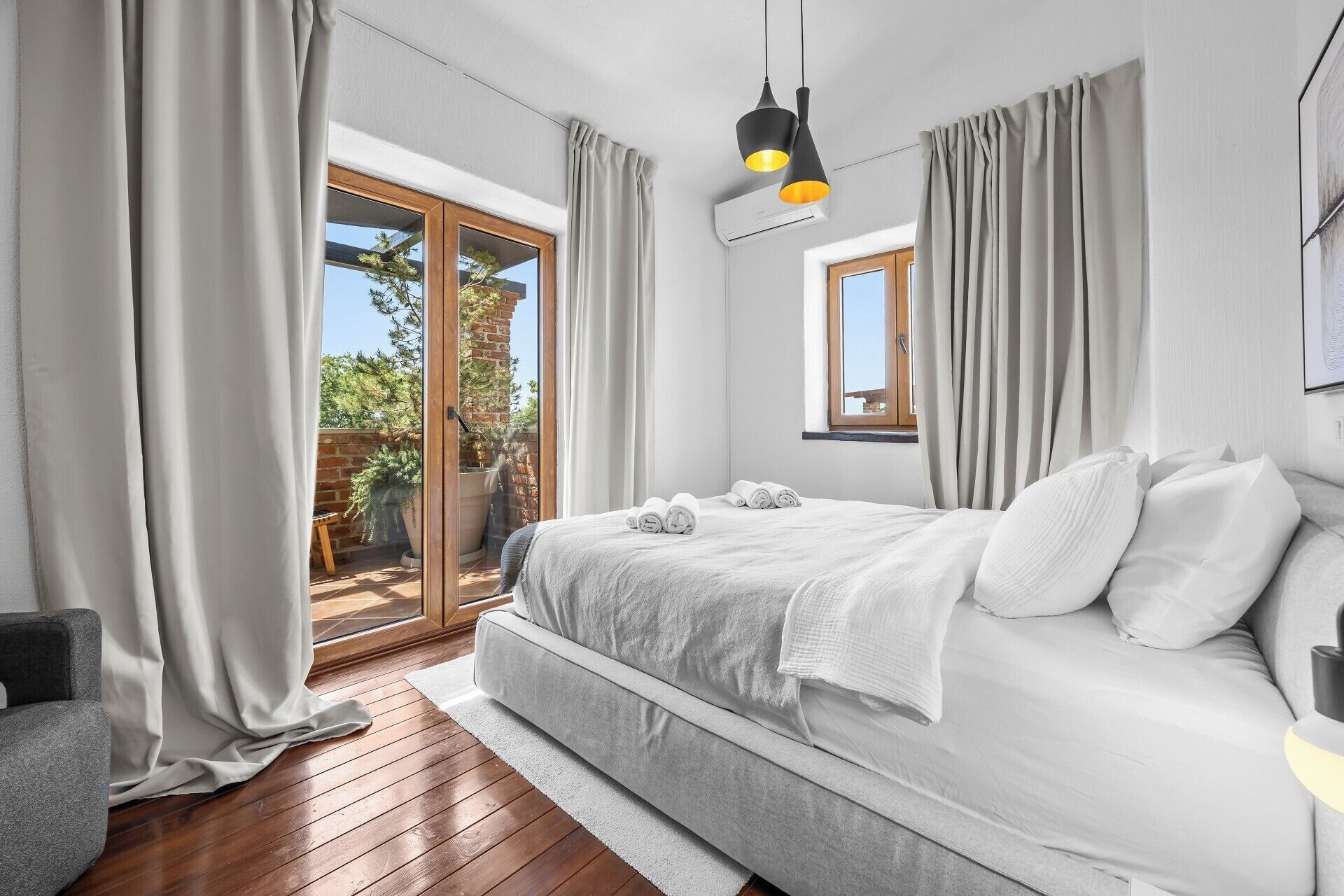Un dormitorio con cama, cortinas, ventana y balcón.