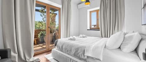 Un dormitorio con cama, cortinas, ventana y balcón.