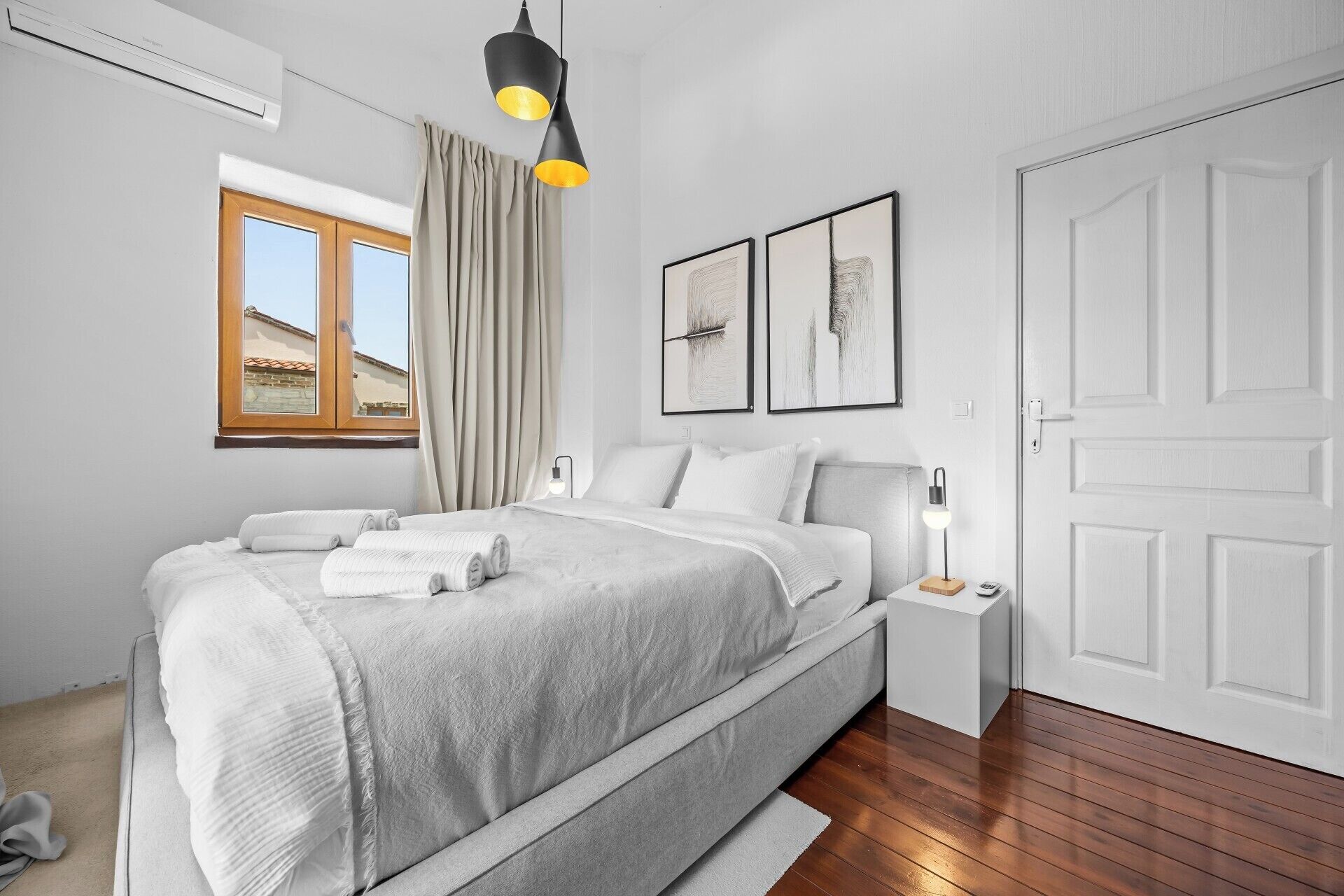 A modern bedroom with a bed, bedside table, lamp, and artwork on the wall.