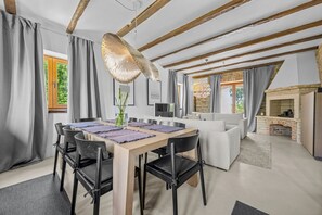 A dining area with a wooden table, black chairs, and a hanging light fixture. - Villa Aurelia – Luxury Istrian Stone Villa with Pool, Jacuzzi and Sauna by Istrabook (Čabrunići)