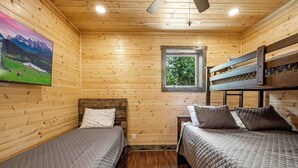 A cabin with two beds, a window, and a painting of a mountain landscape. - Nature’s Ridge | Modern Cabin + Stunning Views (Sevierville)